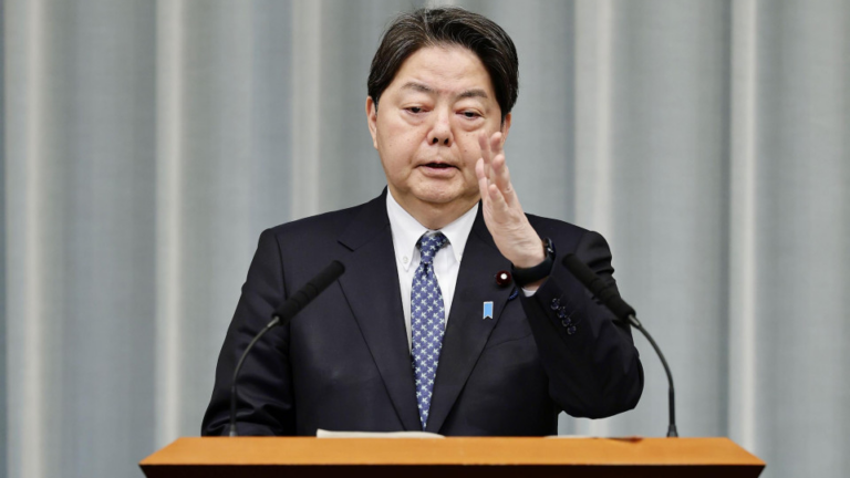 Alt Text: *A person using a smartphone with a cybersecurity alert on the screen, symbolizing Japan’s effort to strengthen online security laws.*